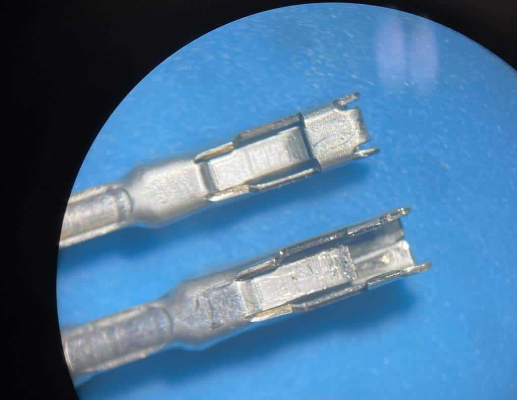 Close-up of a damaged OBD2 terminal next to a new, undamaged terminal, illustrating the difference in condition.