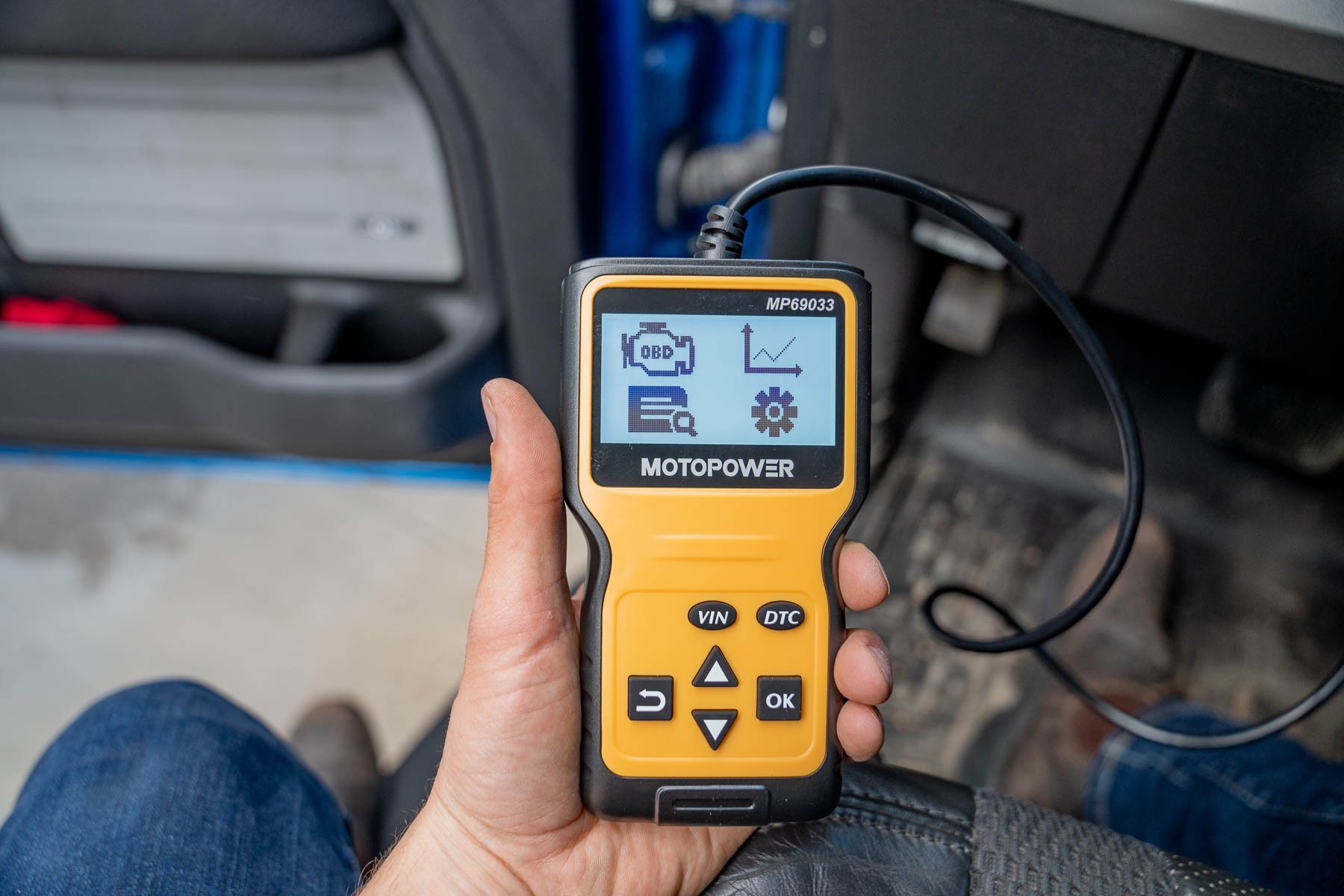 A hand holding an OBD2 scanner, demonstrating its handheld portability and ease of use