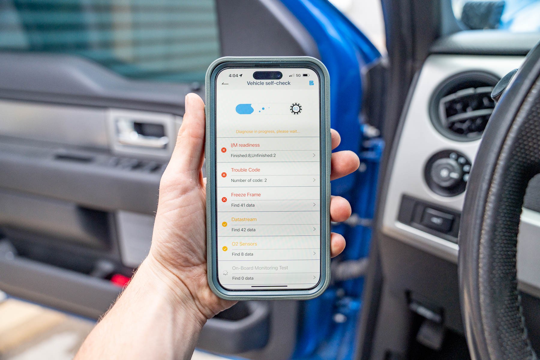 A driver using a smartphone app to access data from a Bluetooth OBD2 scanner connected to their vehicle