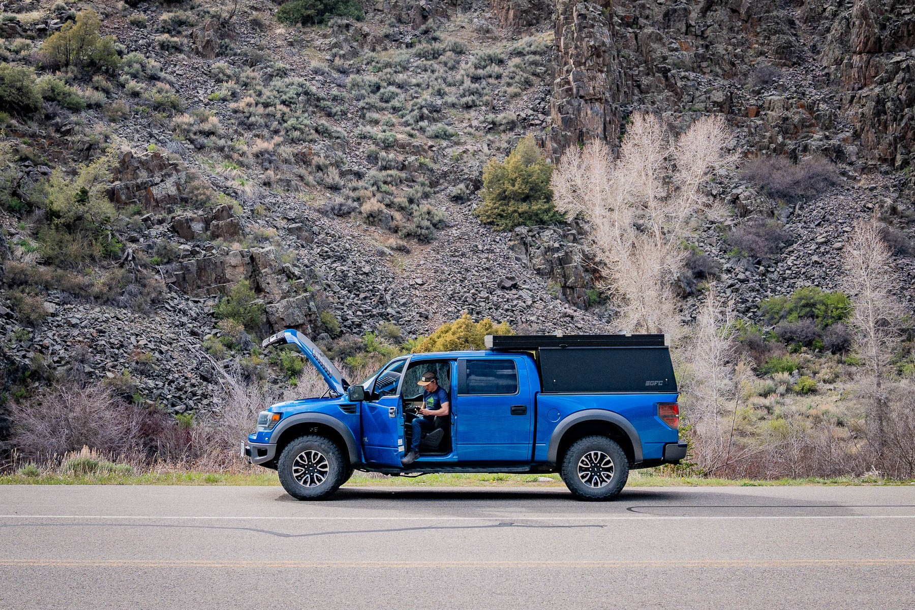 A driver using an OBD2 scanner on the side of a road to diagnose a vehicle issue