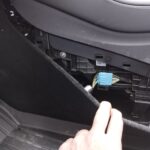 OBD2 port location in a 2024 Tesla Model Y: view of the port in the driver's side footwell