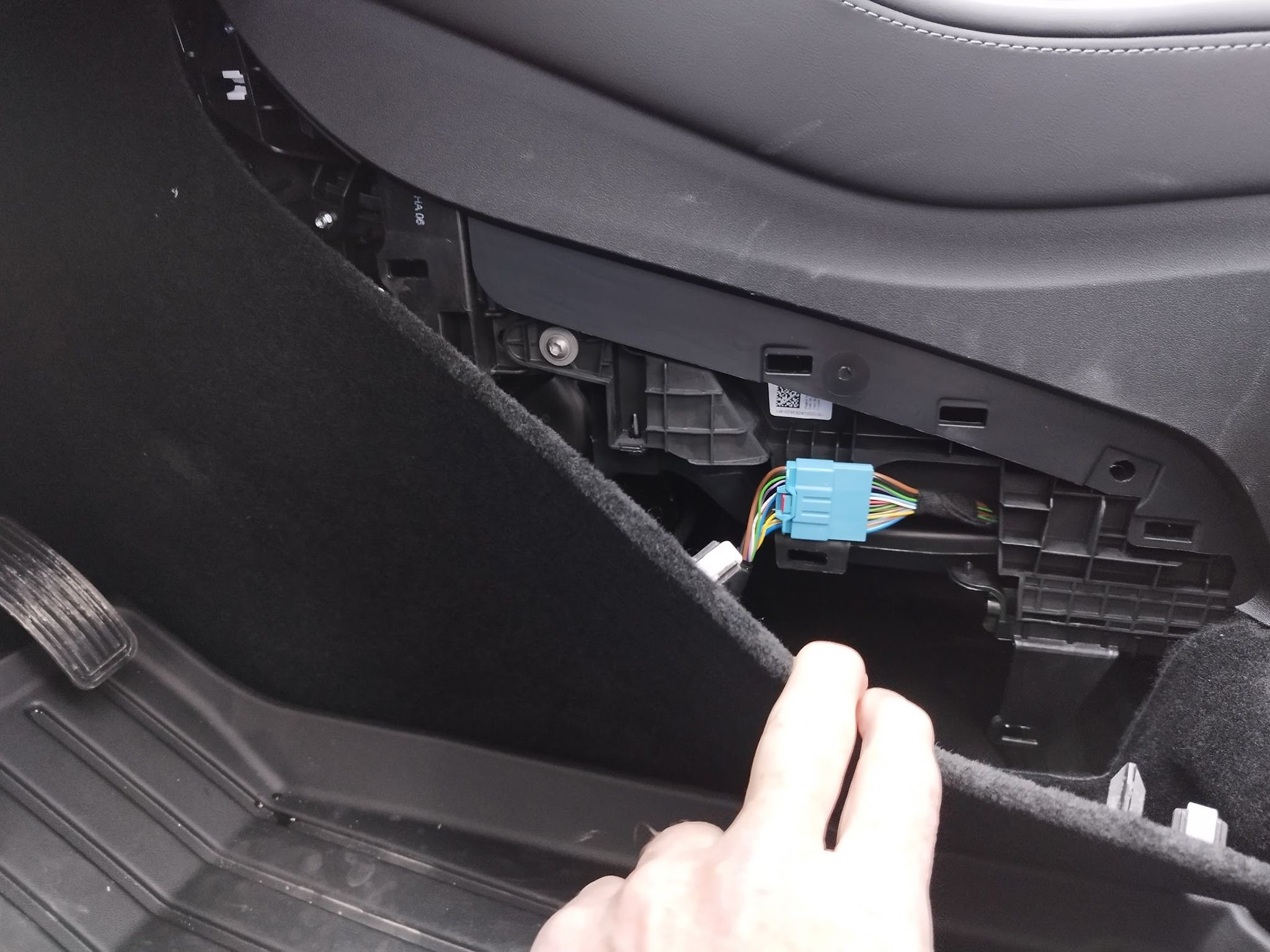 OBD2 port location in a 2024 Tesla Model Y: view of the port in the driver's side footwell